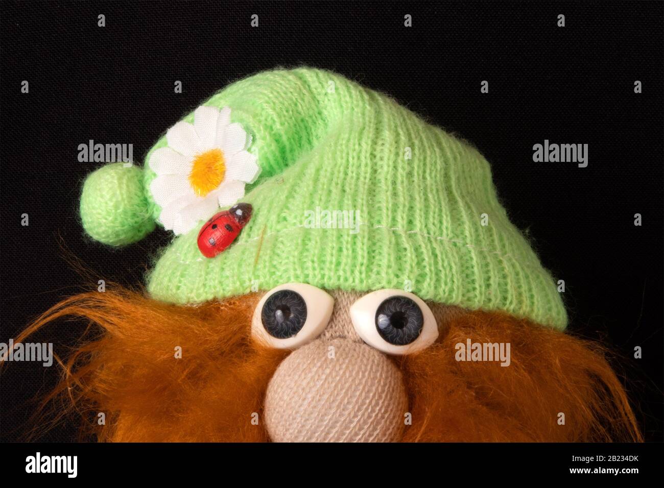 Ausdrucksstarke Augen vor lustigen märchenhaften Gnomen mit rotem schroffen Bart, Designer-Weich-Spielzeug Stockfoto