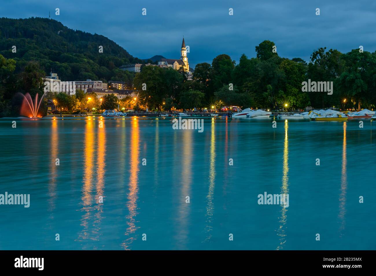 Der See von Annecy und die erhöhte Basilika der Heimsuchung (Basilique de la Visitation), eine katholische Basilika aus dem frühen 20. Jahrhundert, in der Abenddämmerung (Annecy, Frankreich). Stockfoto