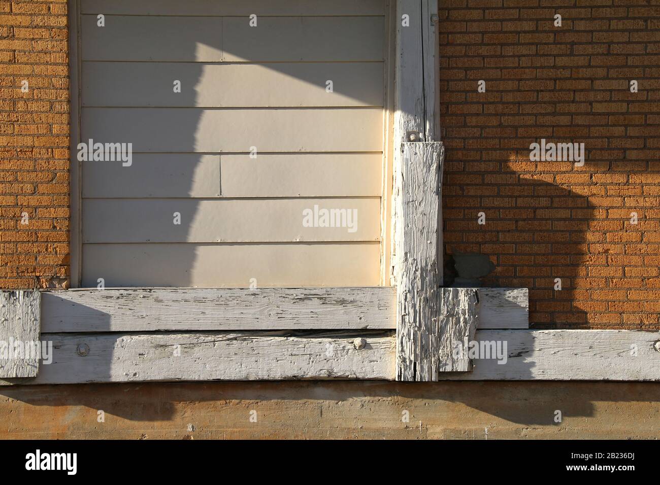 Eine Schiffstür in einem verlassenen Ziegellager an einem sonnigen Nachmittag mit Schatten Stockfoto