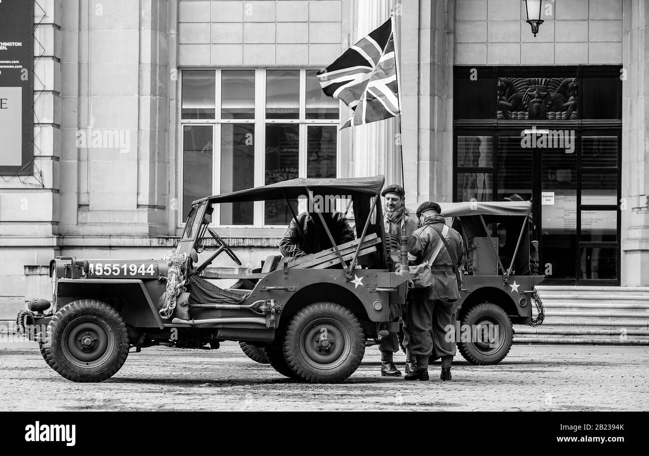 Anmerkung der Redaktion: Das Bild wurde in schwarz-weiße Menschen umgewandelt, die in alten Uniformen in Kriegszeiten gekleidet sind, stehen neben Oldtimern, während sie am Wartime Weekend der vierziger Jahre am Western Approaches HQ in Liverpool teilnehmen. PA Foto. Bilddatum: Samstag, 29. Februar 2020. Der Fotowredit sollte lauten: Peter Byrne/PA Wire Stockfoto