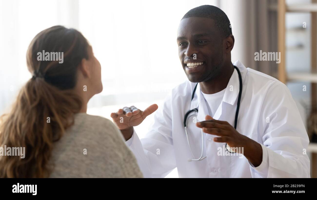 Lächelnder afroamerikanischer Arzt, der bei einem Treffen eine weibliche Patientin berät Stockfoto