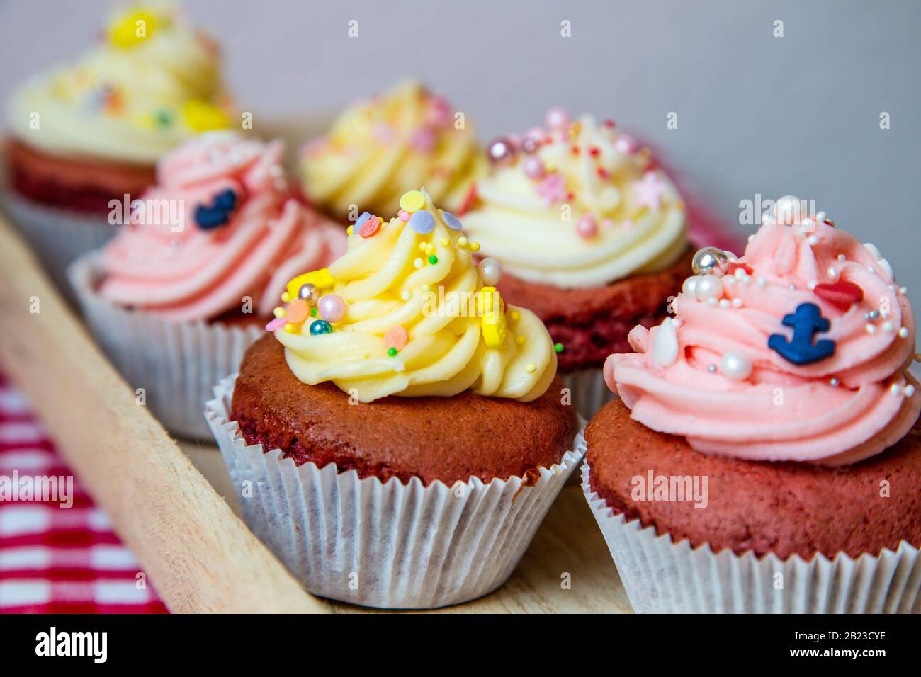 Rote Samtkuchen mit Weiß und Rosettenaufdruck aus einer frischen Buttercreme. Zusammen mit kleinen bunten Einsprengseln wie Anker oder Ananas. Stockfoto