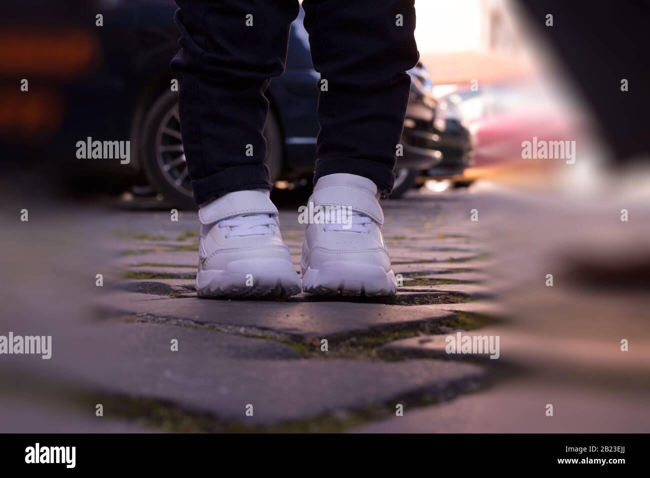 Kinder weiße Sportschuhe Pads Straßenbelag verwischen Jeans kleine Beine Junge stehend Stockfoto