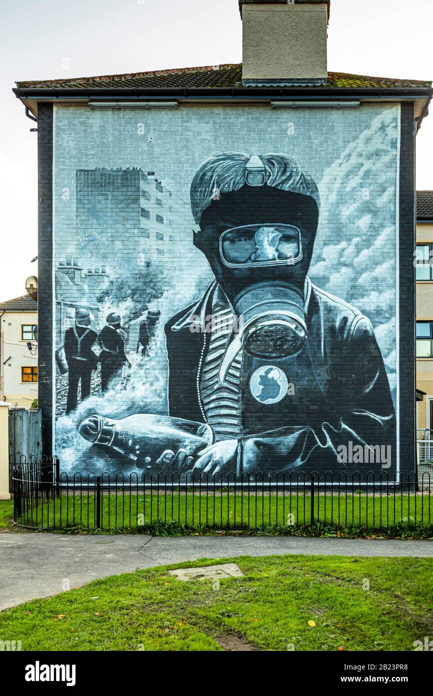 Das "Petrol Bomber"-Mural der Bogside Artists zeigt einen maskierten jungen Mann mit Gasmaske, der einen Molotow-Cocktail wirft, mit drei Figuren, die durch Rauch hinter ihm sichtbar sind – im Bogside-Bereich von Londonderry, County Derry, Nordirland. Das 1994 gemalte Werk gehört zur zwölfteiligen "People's Gallery" in der Rossville Street und erinnert an die Schlacht von Bogside im August 1969. Stockfoto