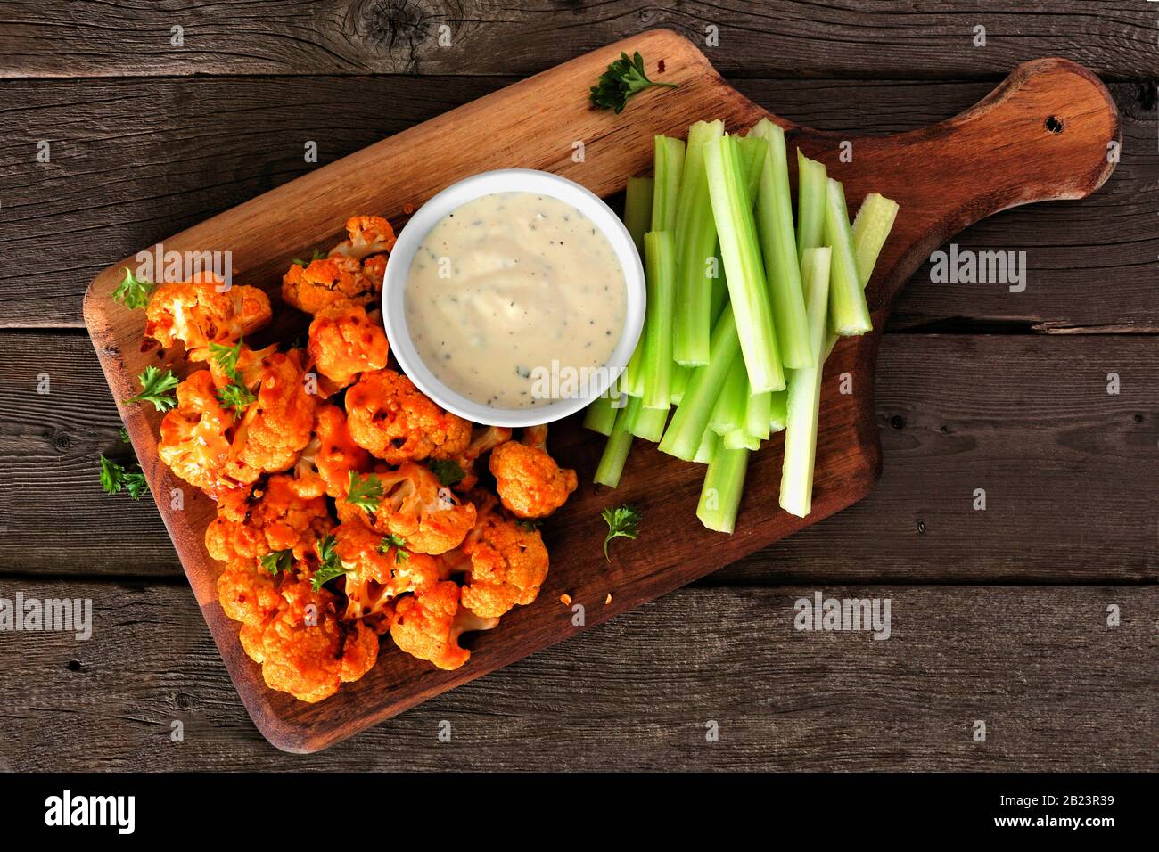 Büffelflügel mit Blumenkohl und Sellerie. Draufsicht auf einem Holzpaddelbrett. Gesundes Essen, pflanzliches Fleisch Ersatzkonzept. Stockfoto