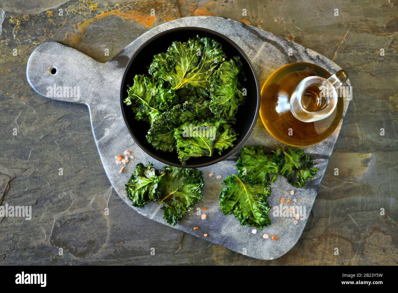 Platte mit gesunden Kale Chips. Draufsicht, auf dunklem Schiefergrund. Stockfoto