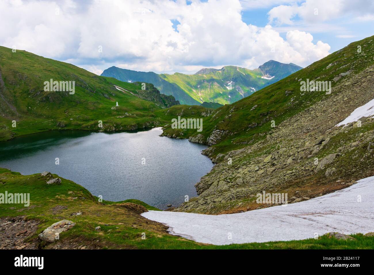 Ziegensee in den fagaras-bergen rumäniens. Beliebtes Reiseziel. Sommerliche Naturlandschaft mit grünem Gras und Schnee. Kante in der Ferne Stockfoto