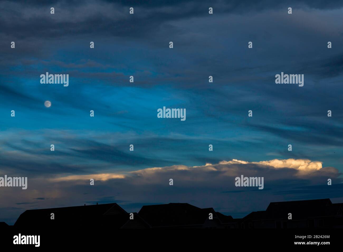 Nachtlandschaft mit blauem Himmel, Mond, hellem Wolkenstreifen und Silhouetten Stockfoto