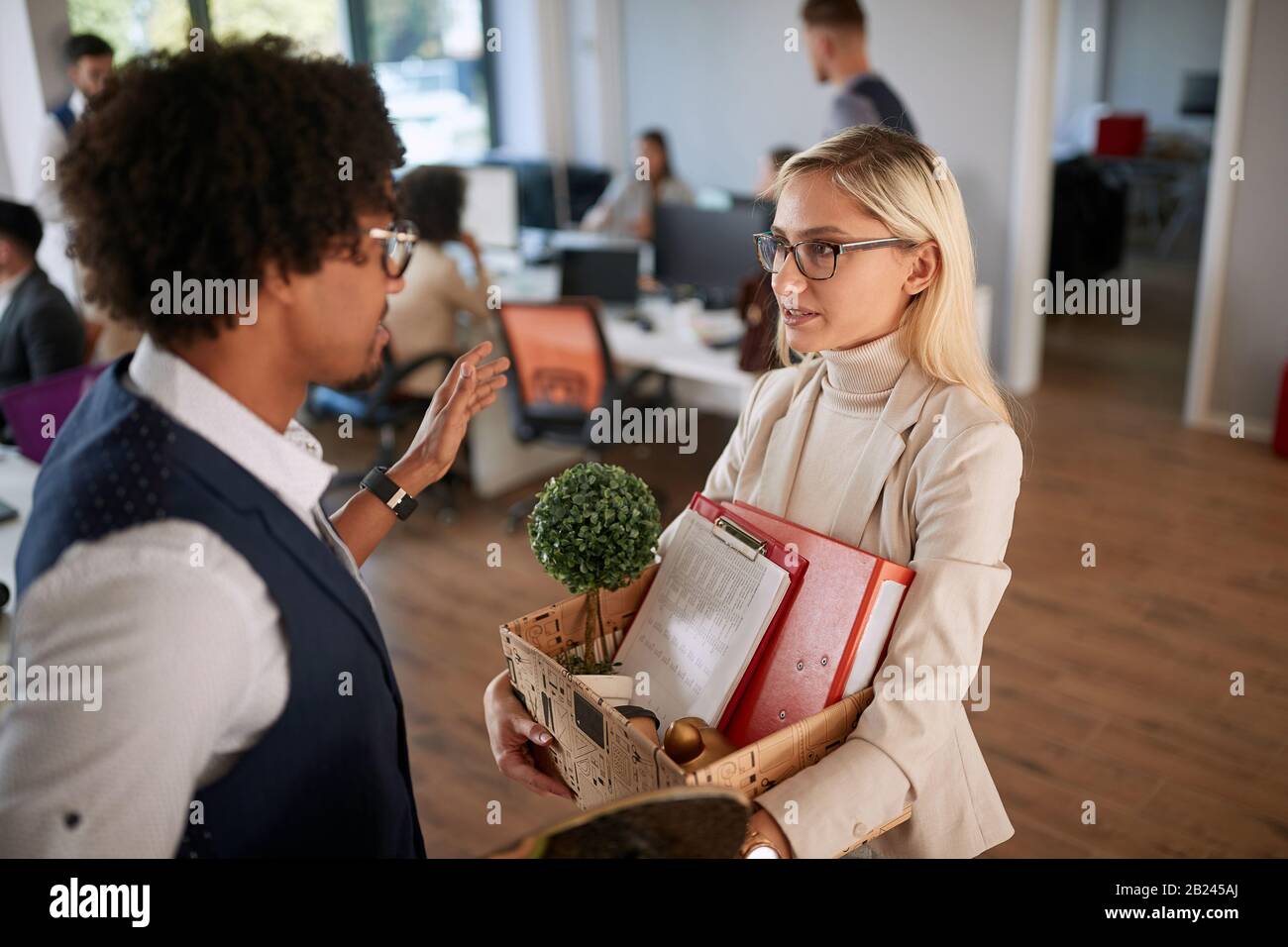 Traurige Frau, die eine Kiste mit Dingen trägt, um bei der Arbeit gefeuert zu werden. Stockfoto