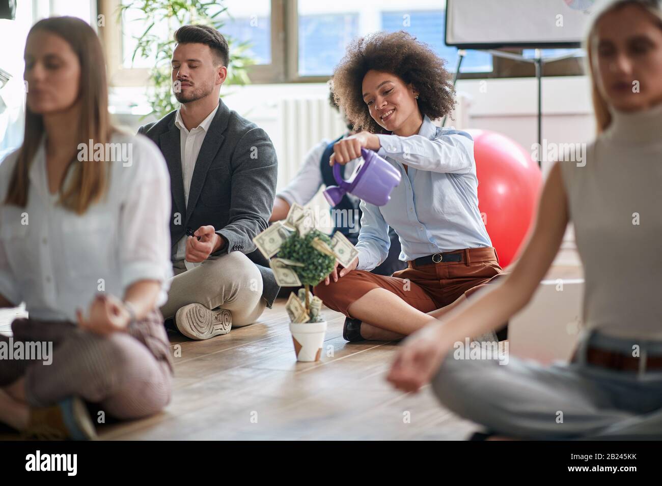 Junge Geschäftsfrau meditiert am Arbeitsplatz, wächst Geld und Geist. Positiver, moderner und harmonischer Mitarbeiter. Stockfoto