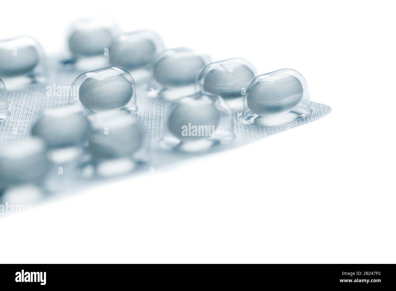 Die geringe Nahaufnahme einer Folienverpackung für Tablettendragees, die auf weißem Hintergrund ohne Schatten und selektive Fokussierung auf ein einzelnes Tablett isoliert sind. Stockfoto