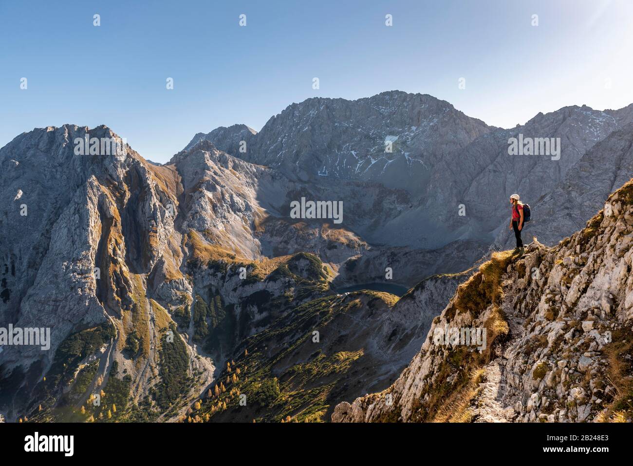 Bergsteiger mit Kletterhelm steht auf einem Felsvorsprung, Wanderweg zur Ehrwalder Sonnenspitze, Ehrwald, Mieminger Kette, Tyrol, Österreich Stockfoto