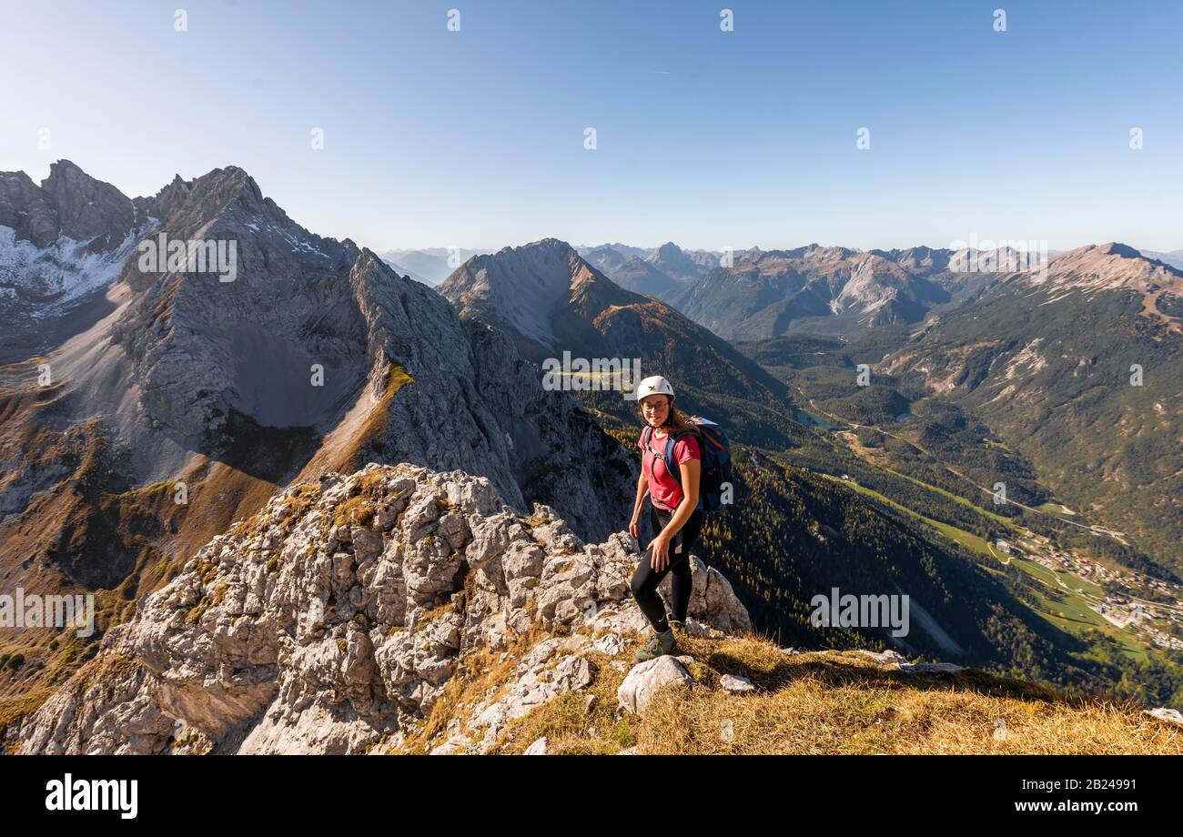 Junge Frau, Bergsteigerin mit Kletterhelm mit Blick auf die Berglandschaft, Wanderung zur Ehrwalder Sonnenspitze, hinter Gruenstein und West Stockfoto