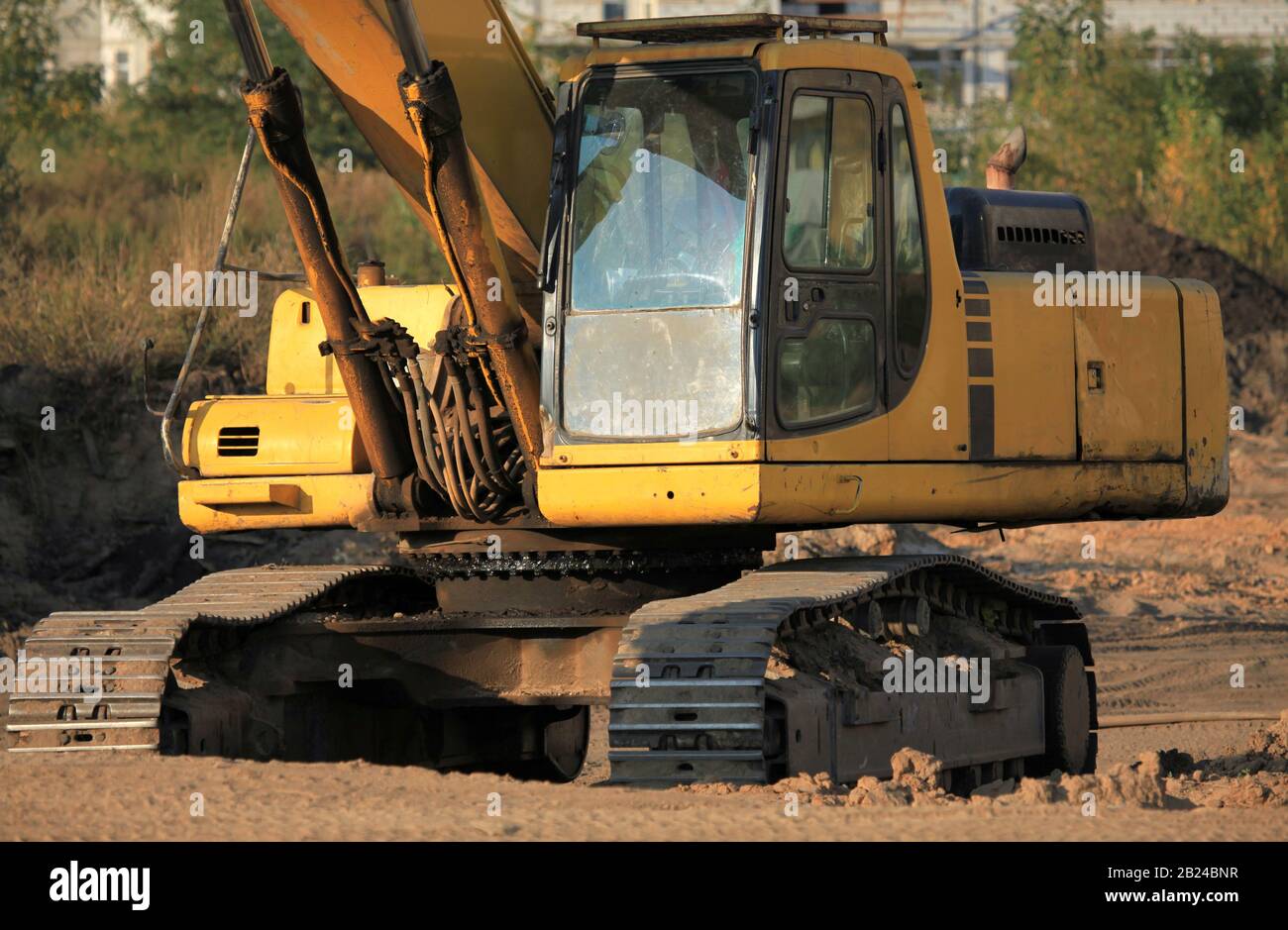 Bagger (Digger) schließen mit einem riesigen Eimer an einer Baustelle. Baumaschinen in der Anlage. Bau einer neuen Wohnanlage Stockfoto