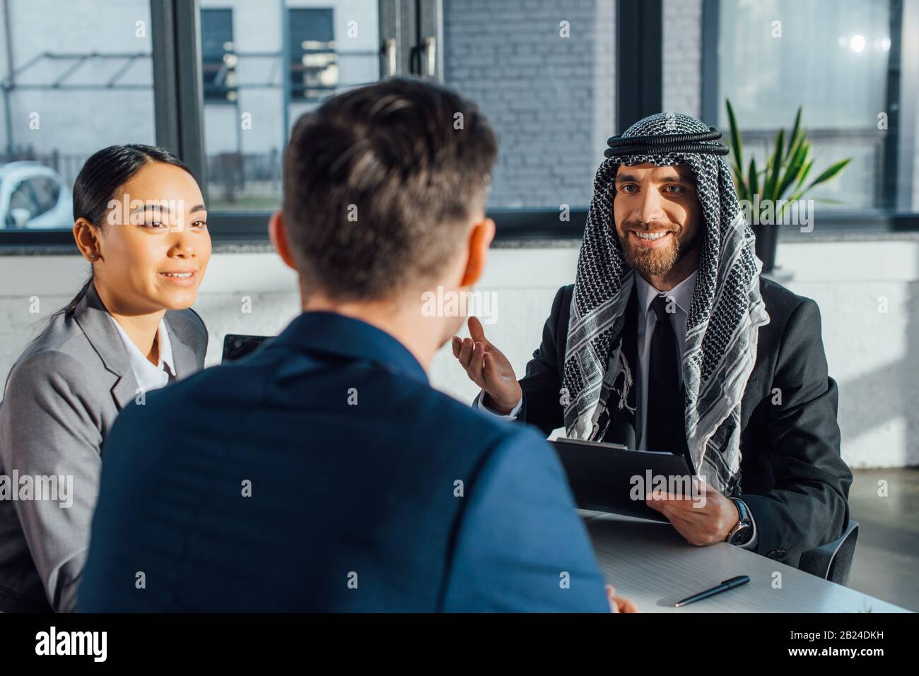 Glückliche multikulturelle Geschäftspartner, die den Vertrag über ein Treffen mit Übersetzern im Büro besprechen Stockfoto
