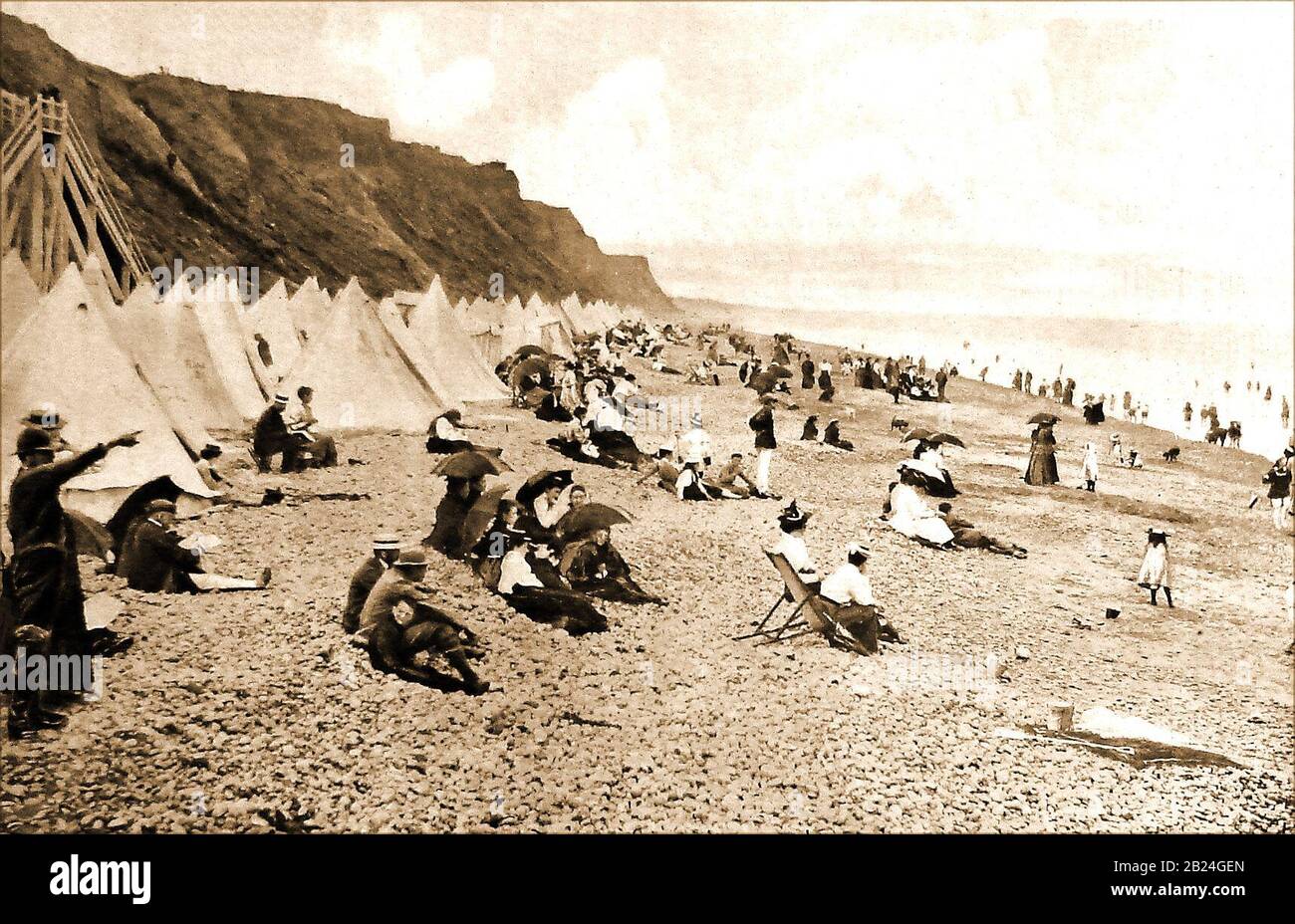 Sheringham Beach (Norfolk, England) im Jahr 1904/05 mit Badegästen Zelte, Sonnenschirme, Liegestühle usw. Sein offizielles Motto lautet "Stute Ditat Pinusque Decorat", lat. "Das Meer bereichert und die Pinienverzauberungen". Sein alter Name im Domesday Book war Silingeham, später Silingeham, Siringeham & Scheringham. Upper Sheringham war traditionell eine Bauerngemeinde, und Lower Sheringham setzte auf die Landwirtschaft mit dem Fischfang. Stockfoto