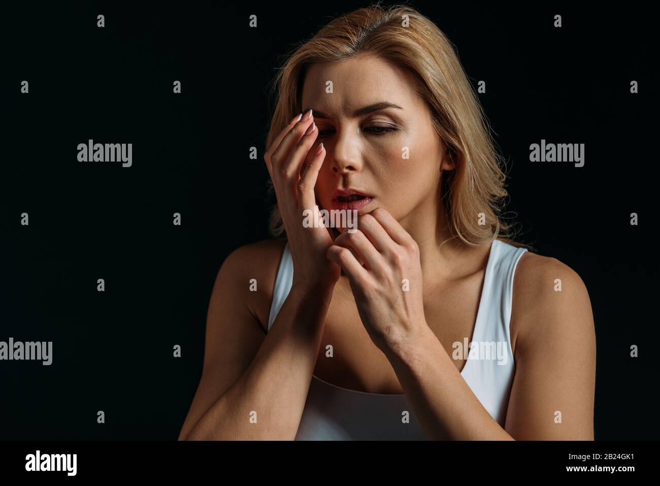 Frau berührt verletzte Hand isoliert auf Schwarz Stockfoto