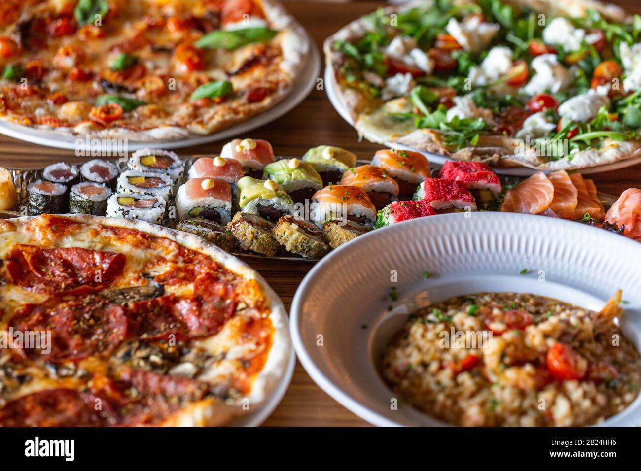 Eine Auswahl an Speisen auf dem Tisch in einem Restaurant mit Pizza und Sushi. Nahaufnahme Stockfoto