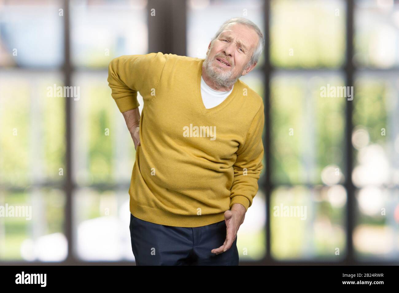 Porträt eines ungesunden alten älteren Mannes mit Schmerzen im unteren Rücken. Stockfoto