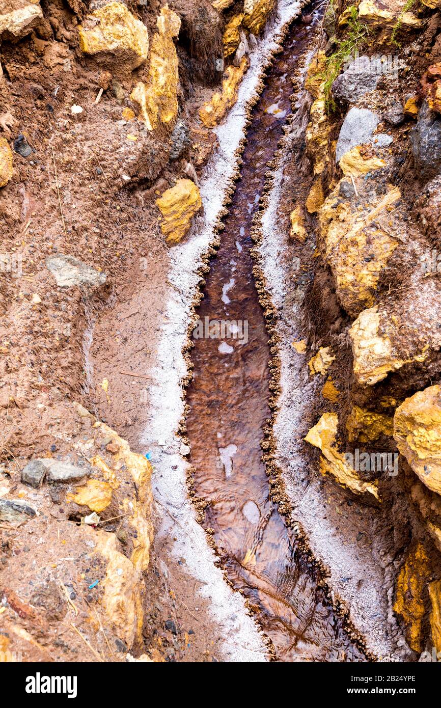 Ein Salzwasserstrom mit kristallisiertem Salz an den Seiten, Salzteiche von Maras (Salinas de Maras), Sacred Valley, Peru Stockfoto