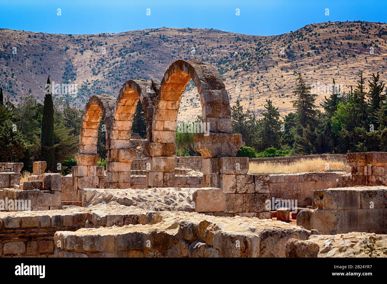 Ruinen von Bögen kleiner Paläste aus der Umayyaden-Ära in Anjar, Bekaa-Tal, Libanon, Naher Osten. Das Anti-Libanon-Gebirge ist im Hintergrund. Stockfoto