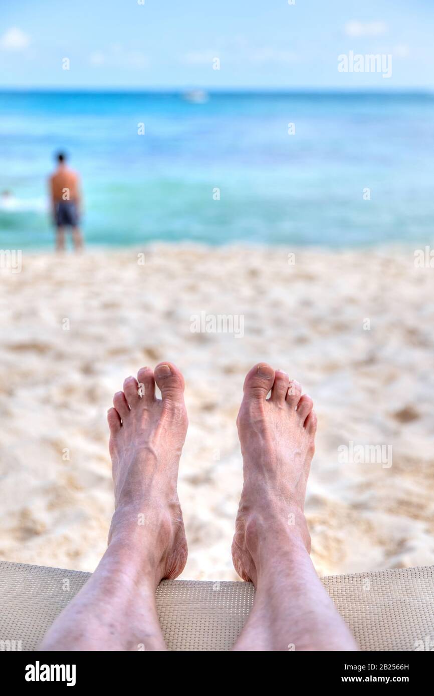 Persönliche Perspektive des Menschen, der sich am Sandstrand erholt, mit Fußblick auf das Meer und Kopieraum. Geschossen in der karibischen Küste Mexikos auf Can Stockfoto