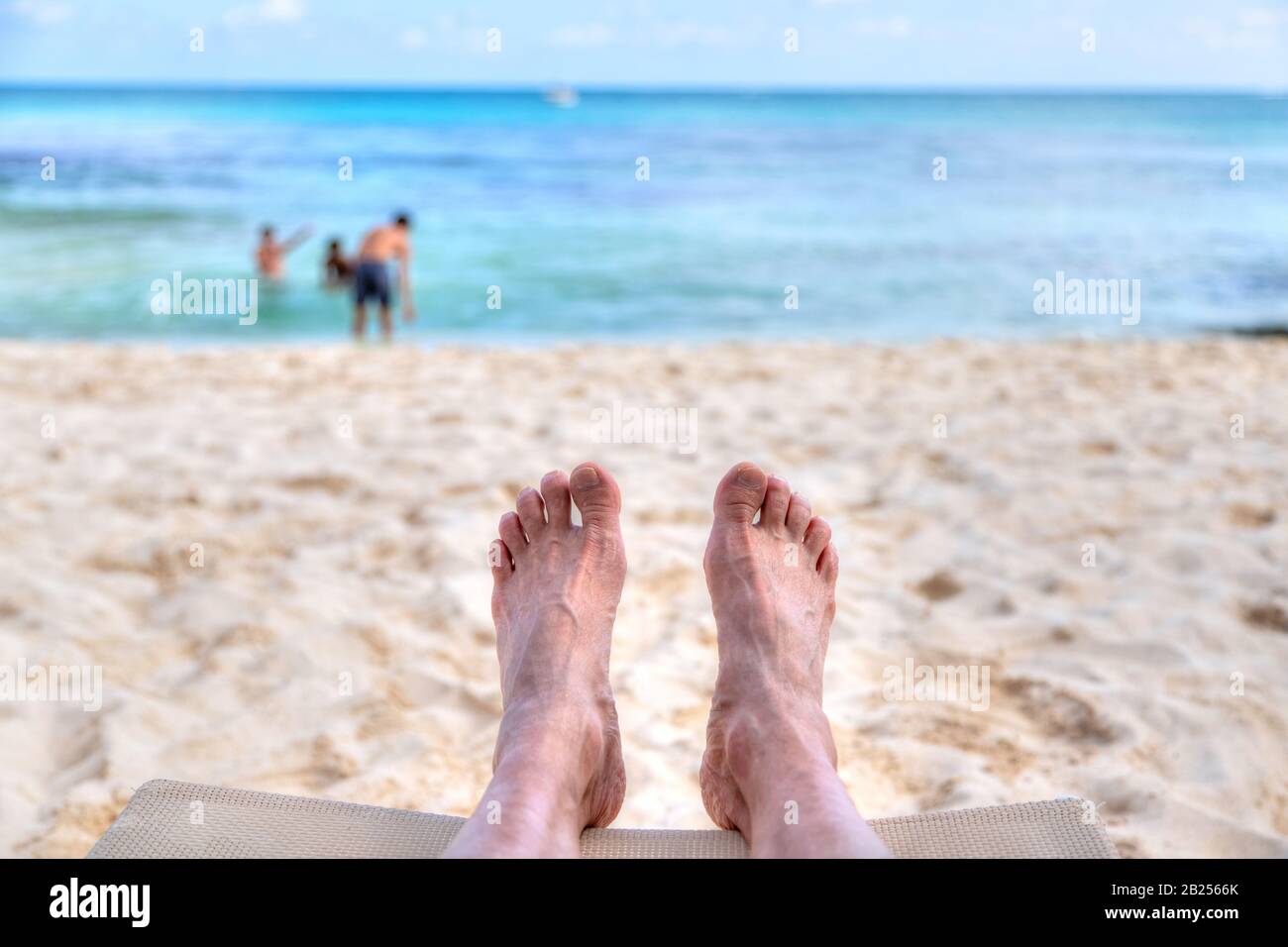 Persönliche Perspektive des Menschen, der sich am Sandstrand erholt, mit Fußblick auf das Meer und Kopieraum. Geschossen in der karibischen Küste Mexikos auf Can Stockfoto