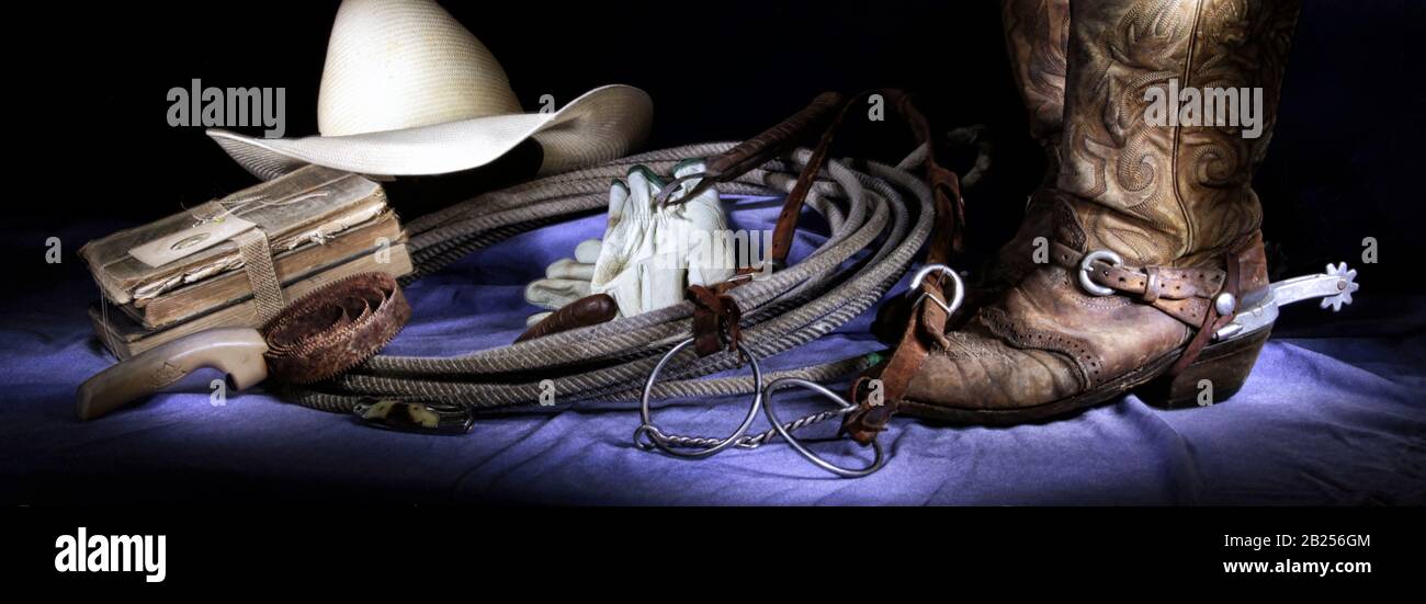 Ein computergroßes Banner zeigt ein westliches Stillleben mit Cowboyhut und Stiefeln mit Spurs, Curry-Pinsel und Lariat sowie Handschuhen und alten Büchern. Stockfoto