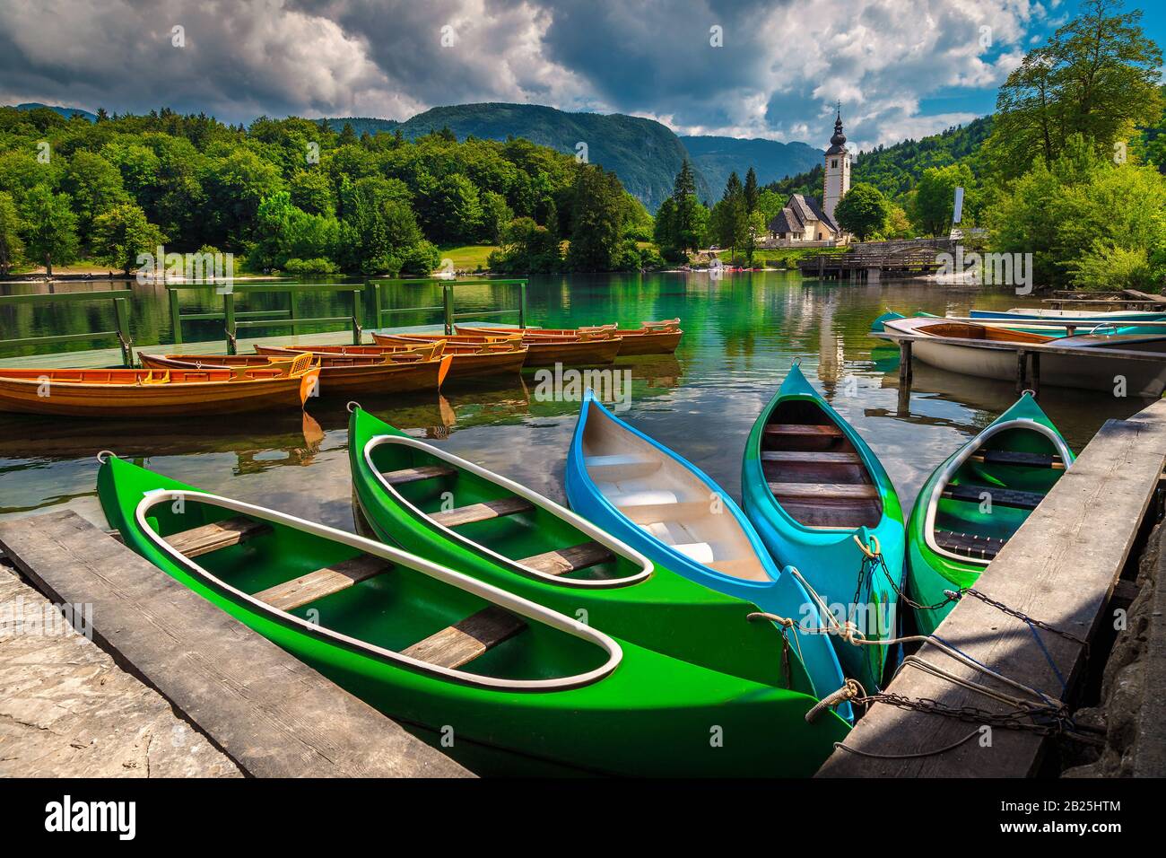 Verankerte bunte Kanus, Kajaks und Holzboote auf dem See. Freizeit- und Sportobjekte am Bohinjer See, Ribcev Laz, Slowenien, Europa Stockfoto