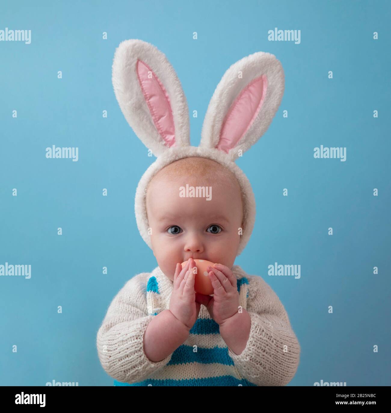 Adliges Baby mit flauschigen osterhasen, die ein osterei tragen Stockfoto