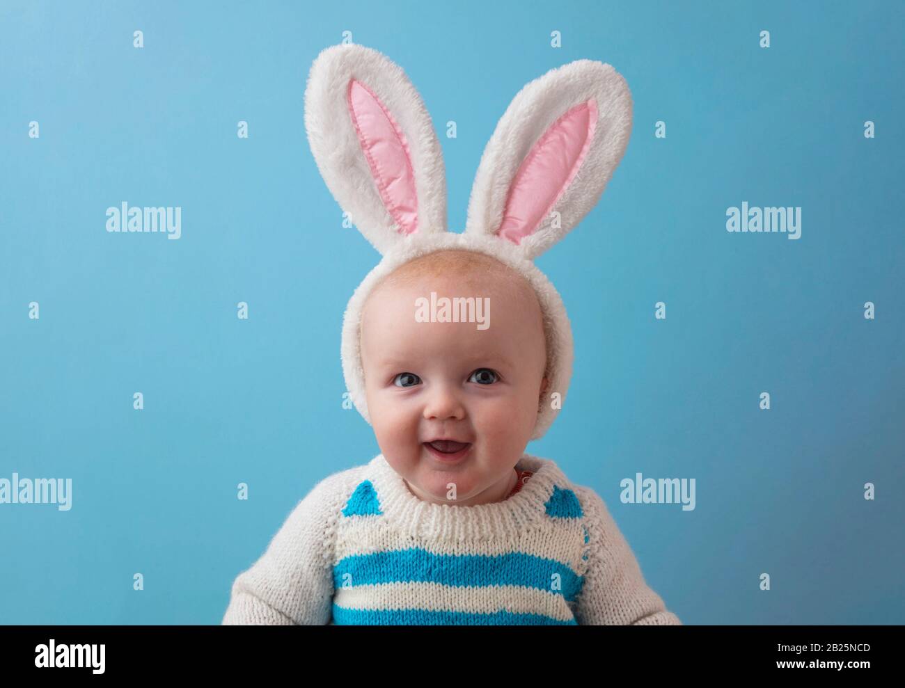 Ein glückliches Baby mit weißen osterhasen, das an der Kamera lächelt Stockfoto