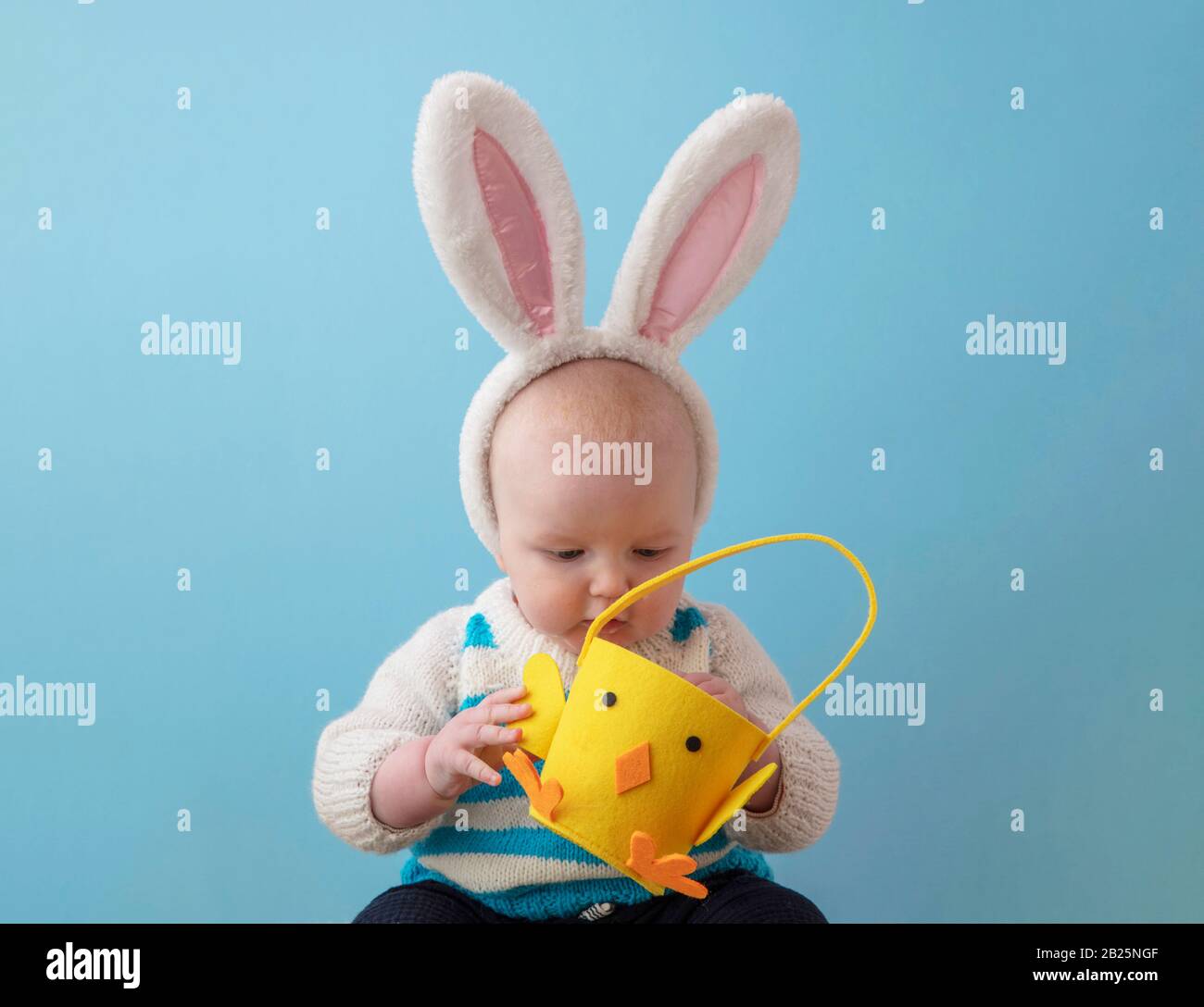 Ein Baby, das süß ist und die easter Hunny Ohren in einen easter Chic Korb schält Stockfoto