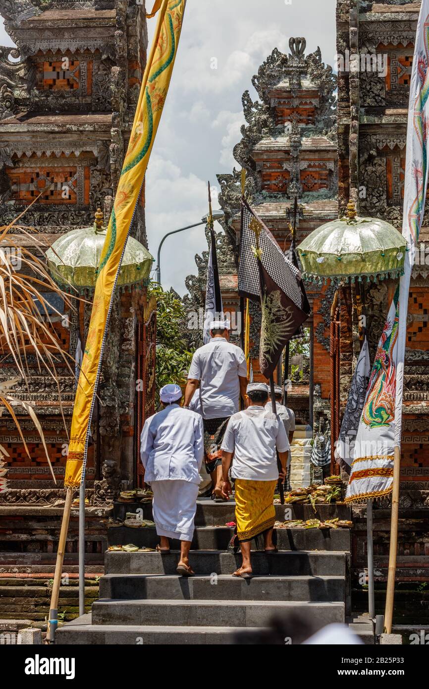 Menschen, die während der Kuningan-Feier in einen balinesischen Hindutempel spazieren. Munggu Dorf, Bali, Indonesien. Vertikales Bild. Stockfoto