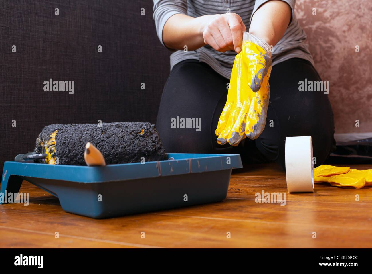 Arbeitsmaler zieht Handschuhe an, Werkzeuge für Hausreparaturen, Wandbemalung. Stockfoto