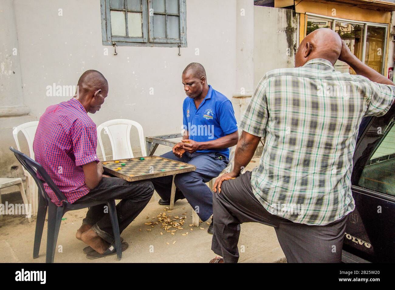 Drei Männer spielen ein Draftspiel auf einer Straße in Nigeria. Stockfoto