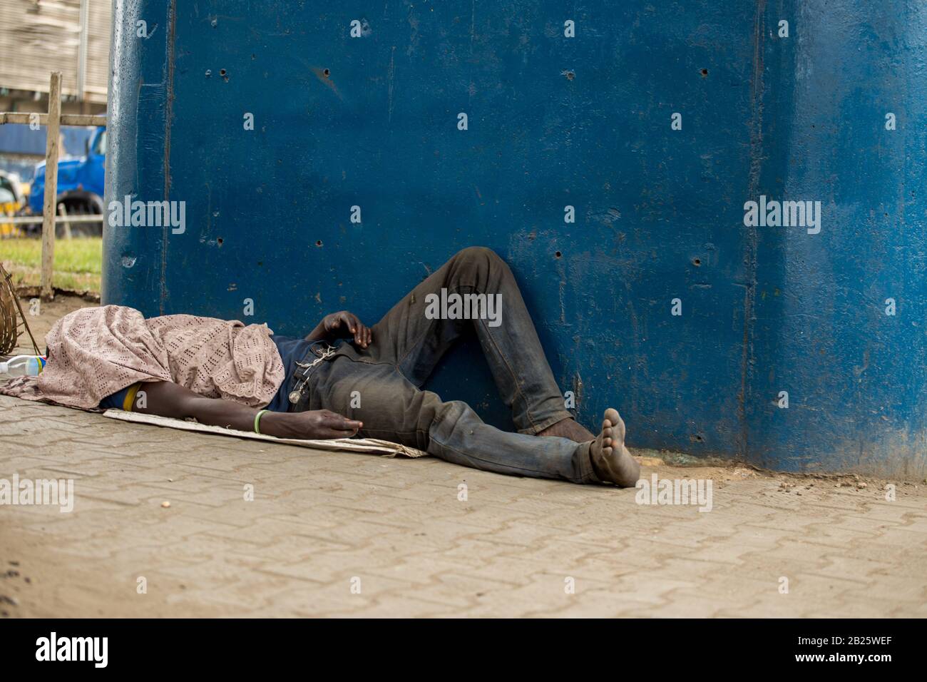 Ein Mann, der öffentlich auf einer Straße in Nigeria schläft. Stockfoto