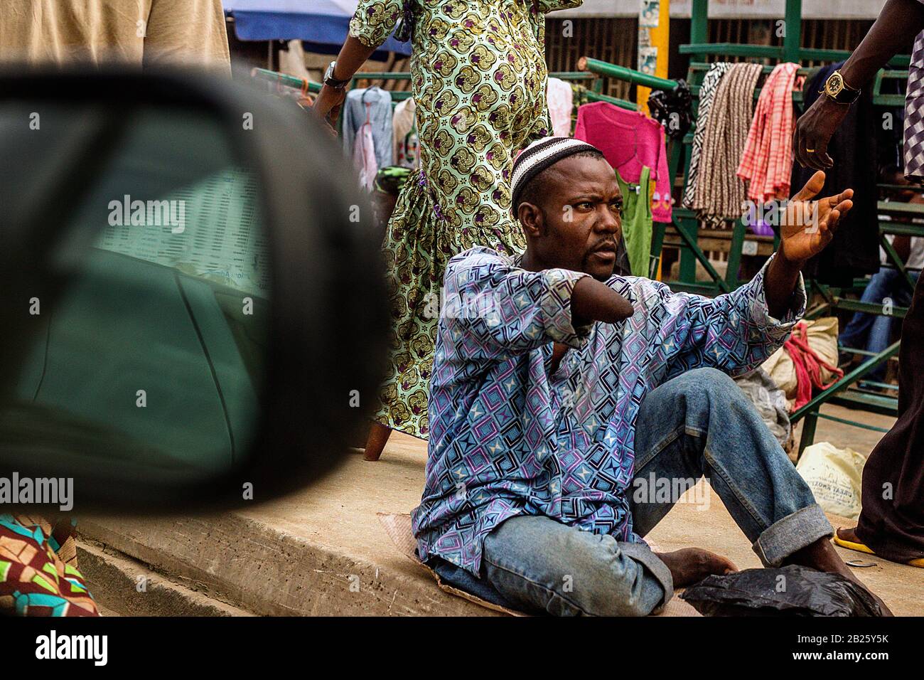 Ein Bettler mit amputierter Hand wird durch das Fenster eines Autos auf einer Straße in Nigeria gesehen. Stockfoto