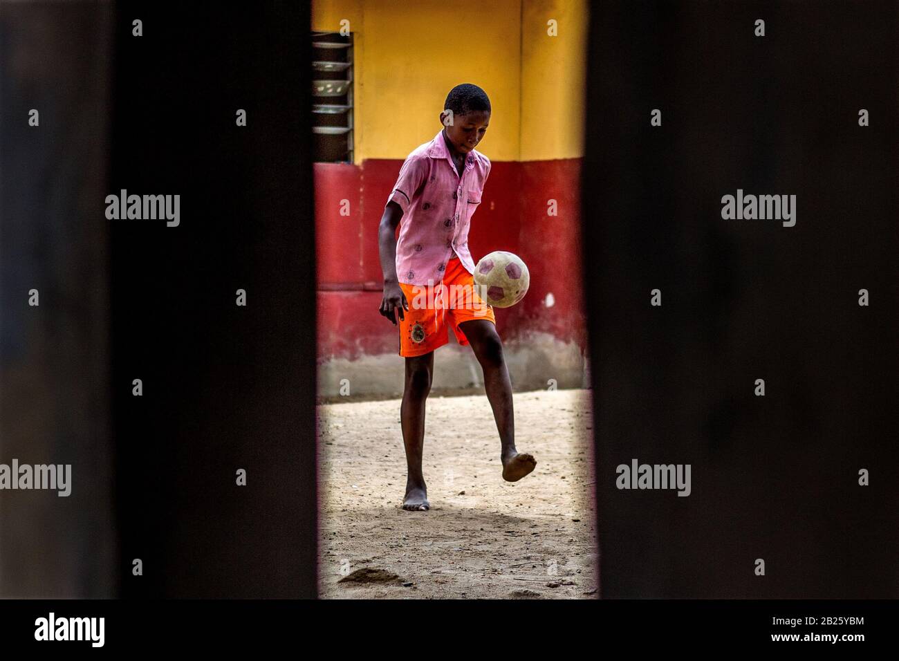 Ein Junge, der in Nigeria auf einer Straße Ball spielt. Stockfoto