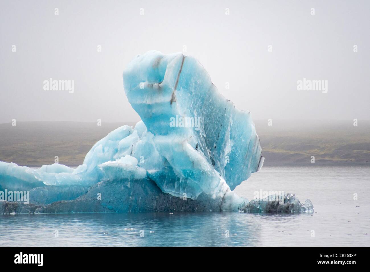 Joekulsarlon Glacier Lagoon tiefblauer Eisberg mit einigen dunklen Schichten vulkanischer Asche Stockfoto