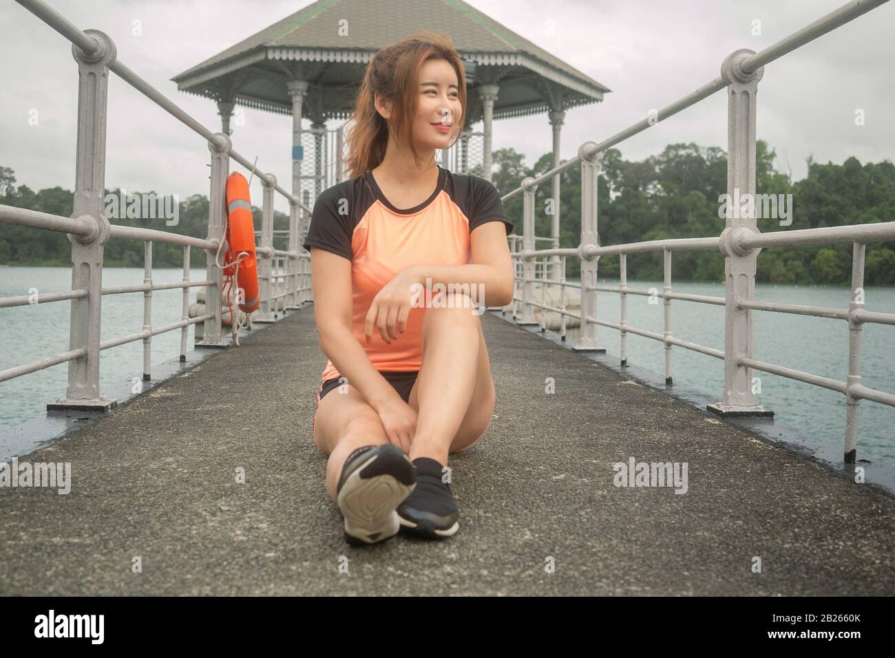 Asiatisch-chinesisches Modell in ihrem Sportoutfit genießen kühle Windblasen im Naturpark nach Joggen im Naturreservoir am frühen Morgen in Singapur Stockfoto