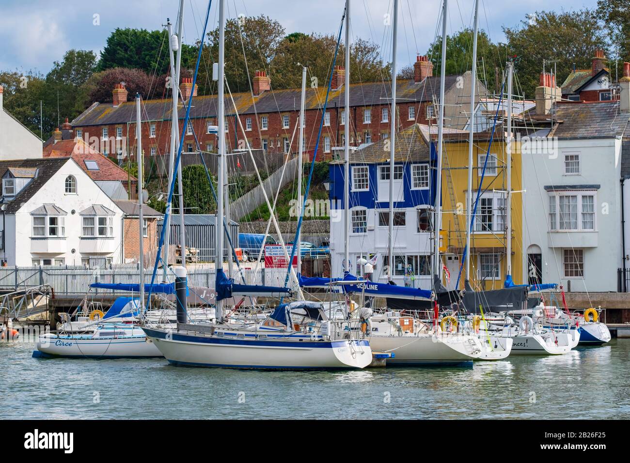 Segelyachten und Boote im Weymouth Harbour mit bunten Häusern an der Jura-Küste von Dorset, South West, Großbritannien Stockfoto