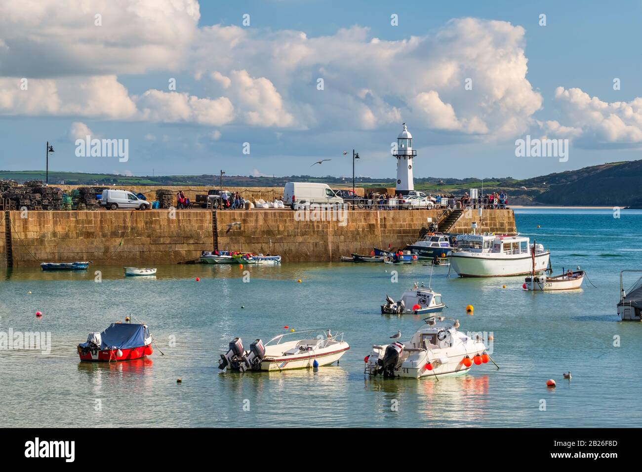 ST Ives Harbour Beach, mit Booten im Hafen mit Smeatons Pier und St Ives neuem Leuchtturm, blauem Himmel, blauem Meer, Cornwall, South West, Großbritannien Stockfoto