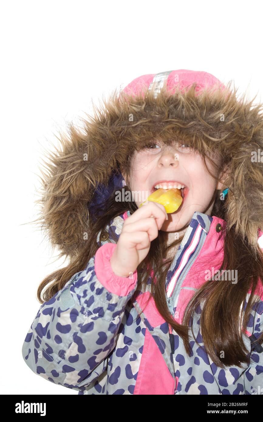 Junges Mädchen, das Eis in der Winterjacke mit Kapuze oben isst Stockfoto