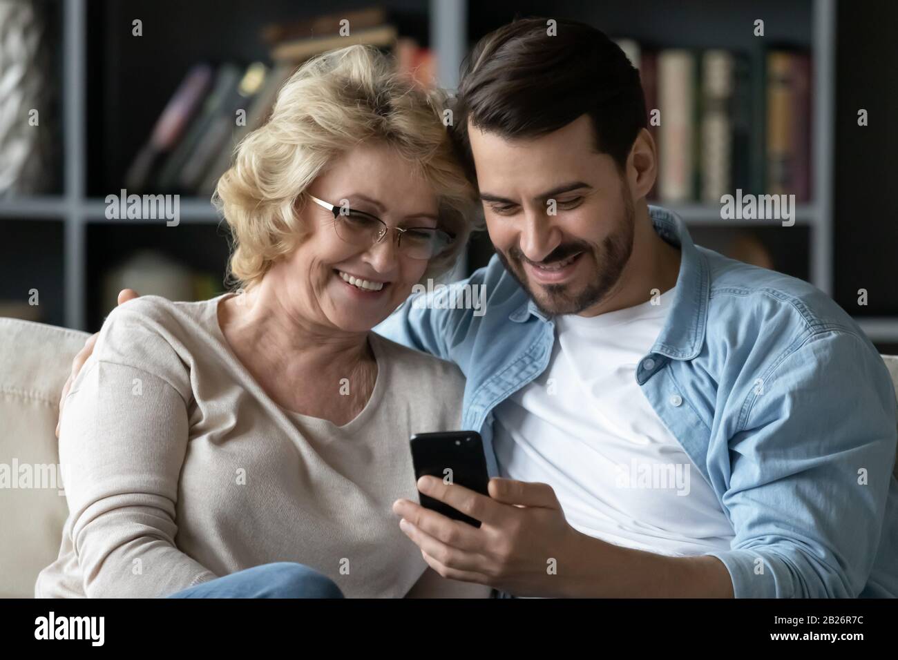 Lächelnde Mutter und Erwachsene Sohn mit Smartphone zusammen Stockfoto