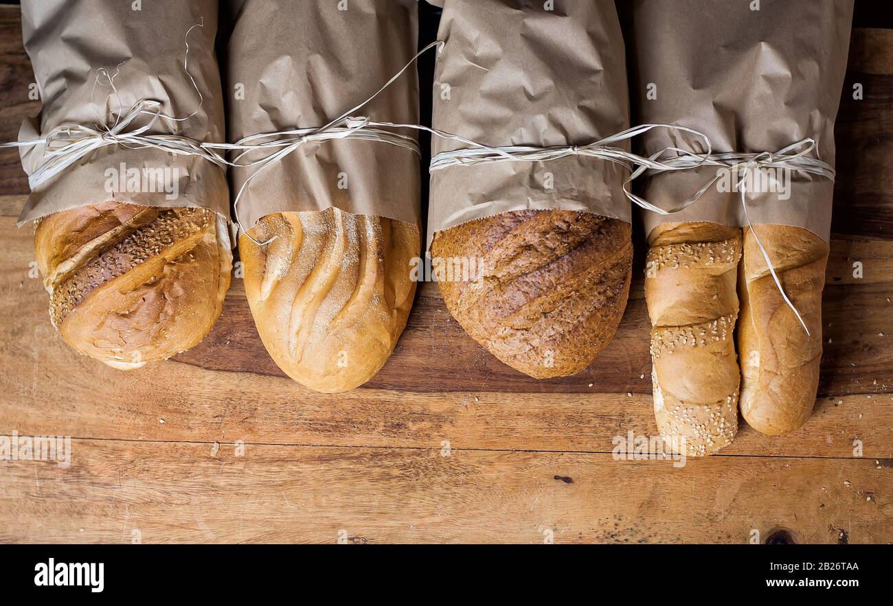 Verschiedene frisch gebackene Brote in Papiertüten auf Holztisch. Freier Speicherplatz. Stockfoto