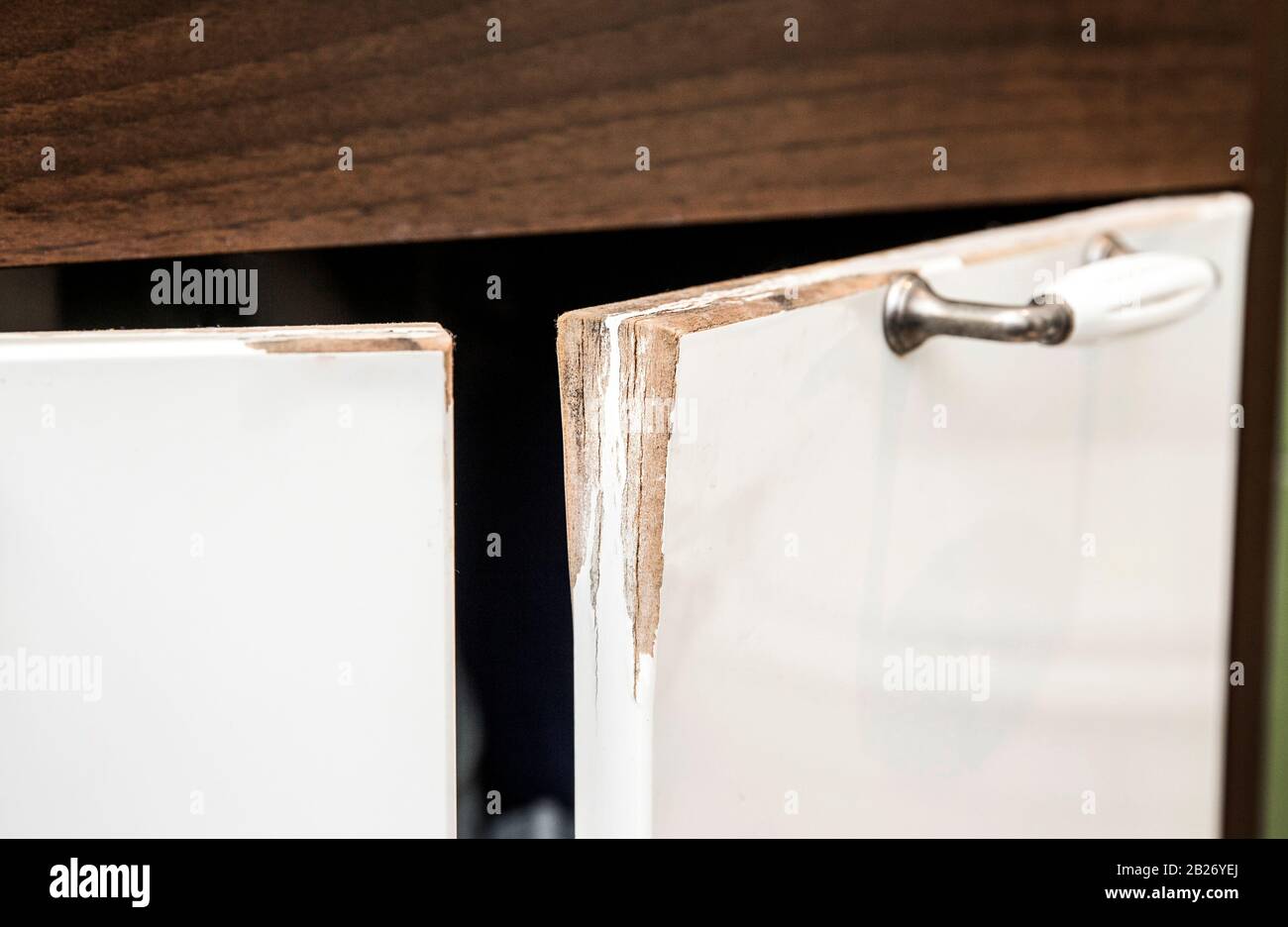 Wasser beschädigte hochglänzende weiße MDF-Badezimmer-Schranktür mit Zierleiste. Feuchtes Konzept für den Zustand des Badezimmers. Stockfoto