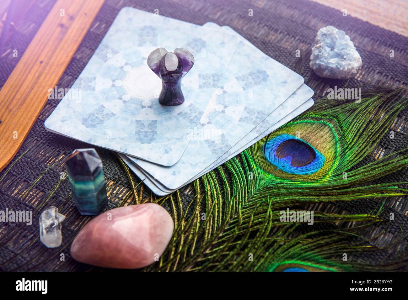 Deck mit selbstgemachten Engelskarten aus Divination auf schwarzem Tisch, umgeben mit Halbedelsteinkristallen. Selektiver Fokus auf Amethys Kristallengel. Stockfoto
