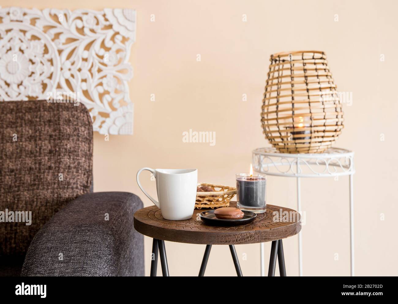 Modernes, minimalistisches Wohnzimmer mit dekorativen Elementen im asiatischen Stil. Geschnitzte Wandtafel, Bambuskerze Laterne, kleiner Holzseitentisch. Stockfoto