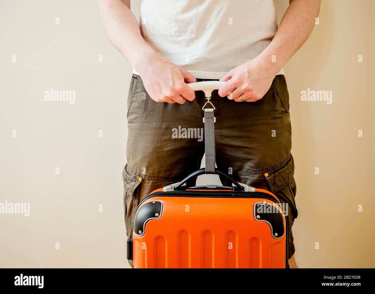 Mann Tourist nutzt digitale Gepäckwaage zu Hause, um Gepäck zu wiegen, um Übergepäck im Flughafenkonzept zu vermeiden. Reduzieren Sie den Stress auf Reisen. Stockfoto