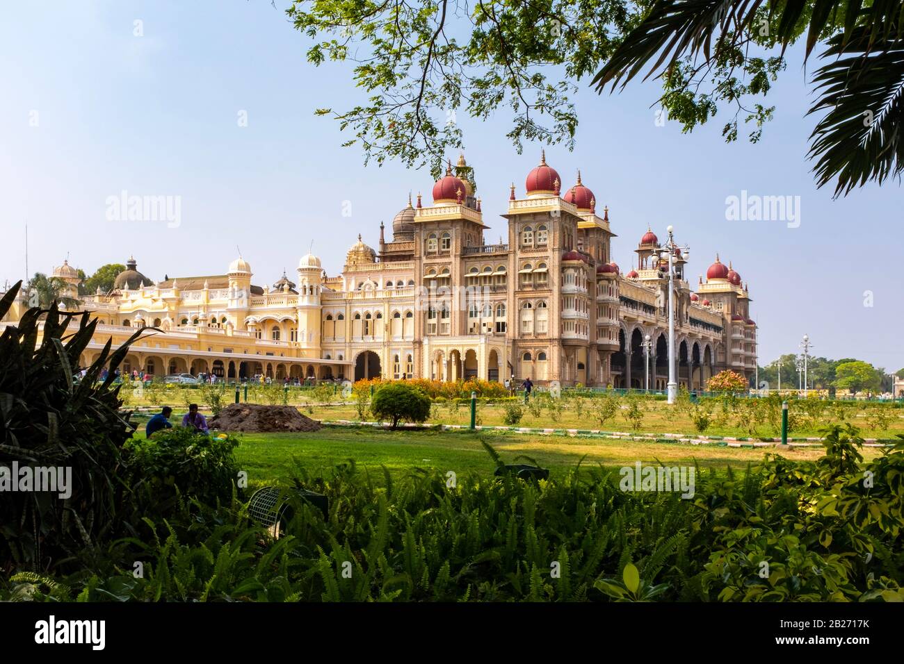 Bäume, die einen Blick auf den Mysore-Palast mit nicht erkennbaren Menschen weit im Hintergrund, Indien, einrahmen Stockfoto